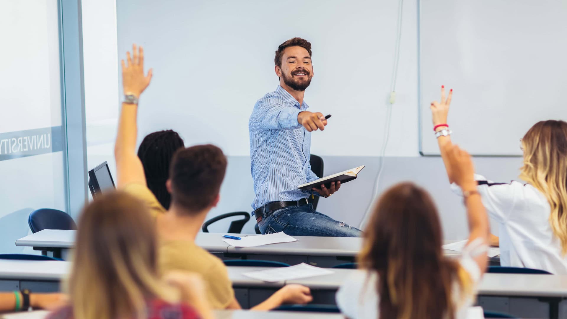 Gruppe von Studenten, die während einer Vorlesung die Hände heben